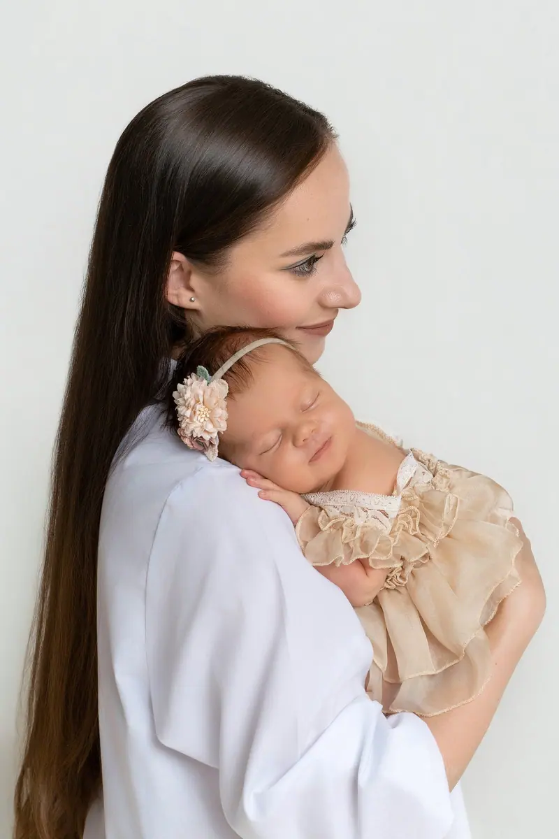 Fotenie mama a baby — mama v bielej košeli drží bábätko v krémových šatočkách