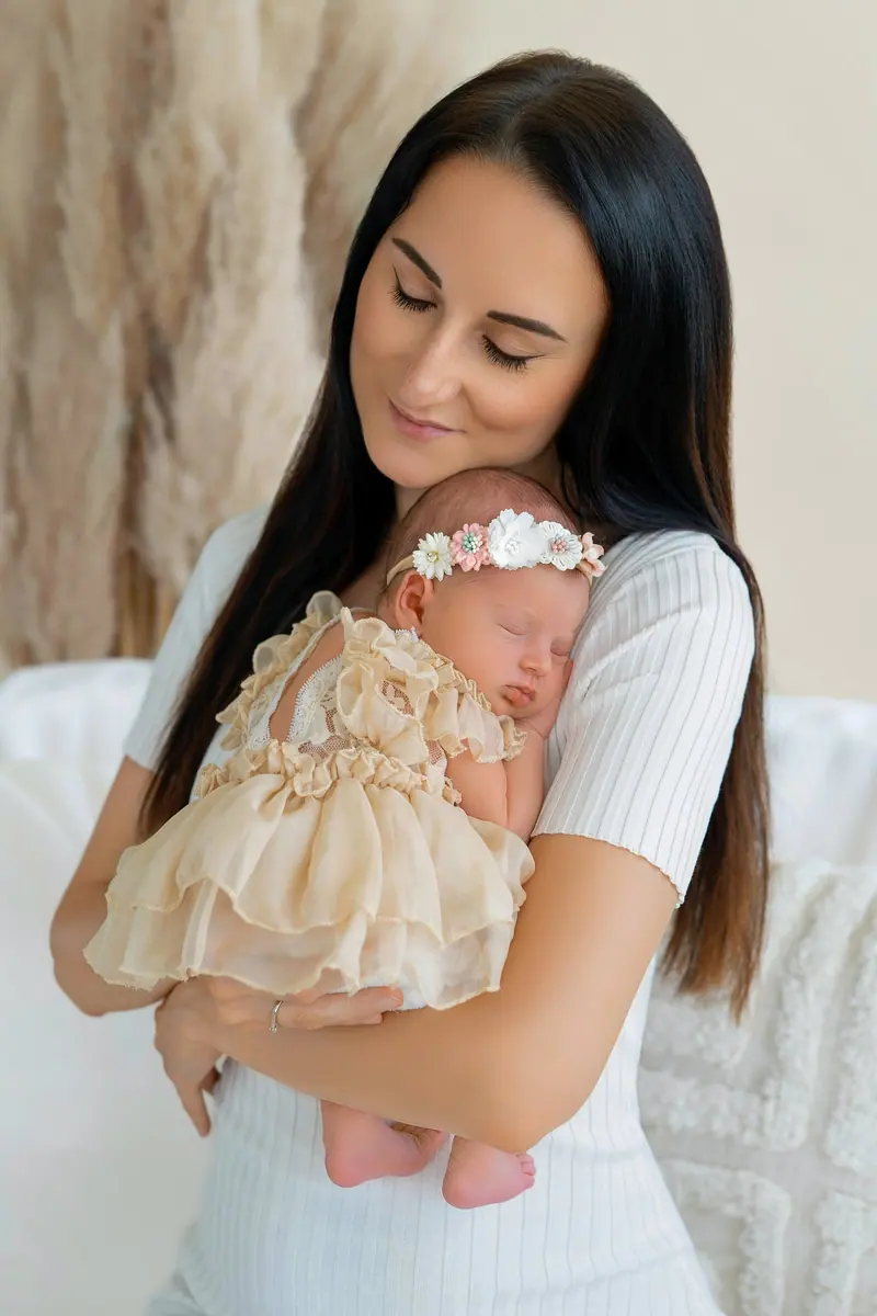 Fotenie mama a baby — mama v bielom drží bábätko, béžové pozadie s pampas trávou
