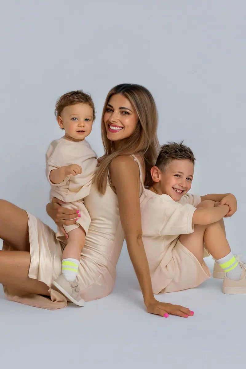 Fotenie mama a baby — mama s dvomi synmi, sediaci, sivé pozadie