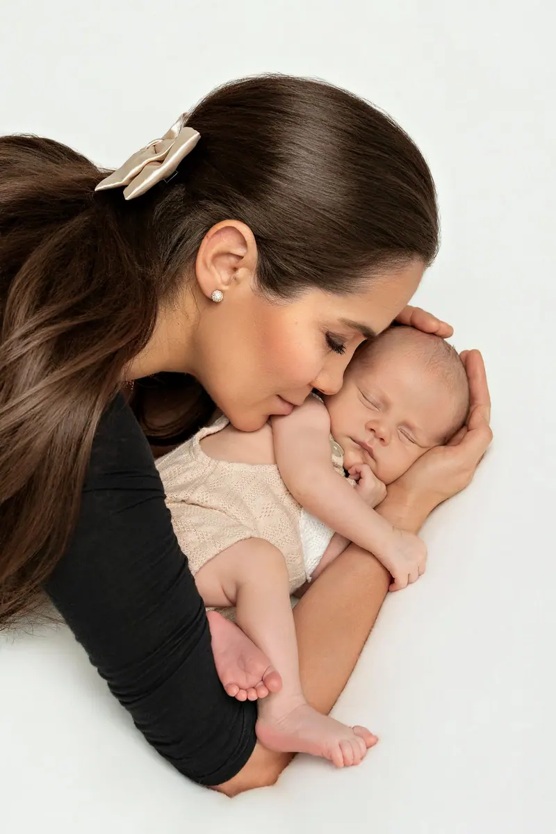 Fotenie mama a baby — mama v čiernom bozkáva novorodenca