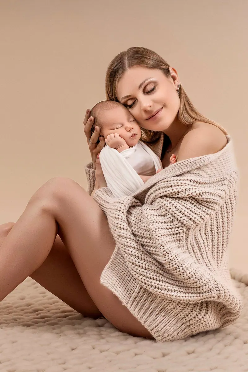 Fotenie mama a baby — mama v pletenom svetri sedí s novorodencom pri tvári