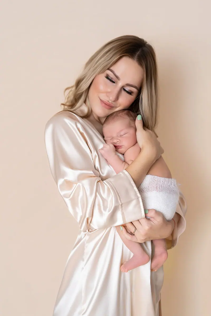 Fotenie mama a baby — mama v saténovom župane drží novorodenca