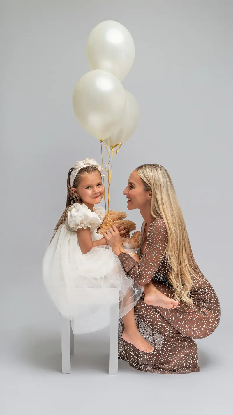 Fotenie mama a baby — mama a dcérka s bielymi balónmi, sivé pozadie, široký záber