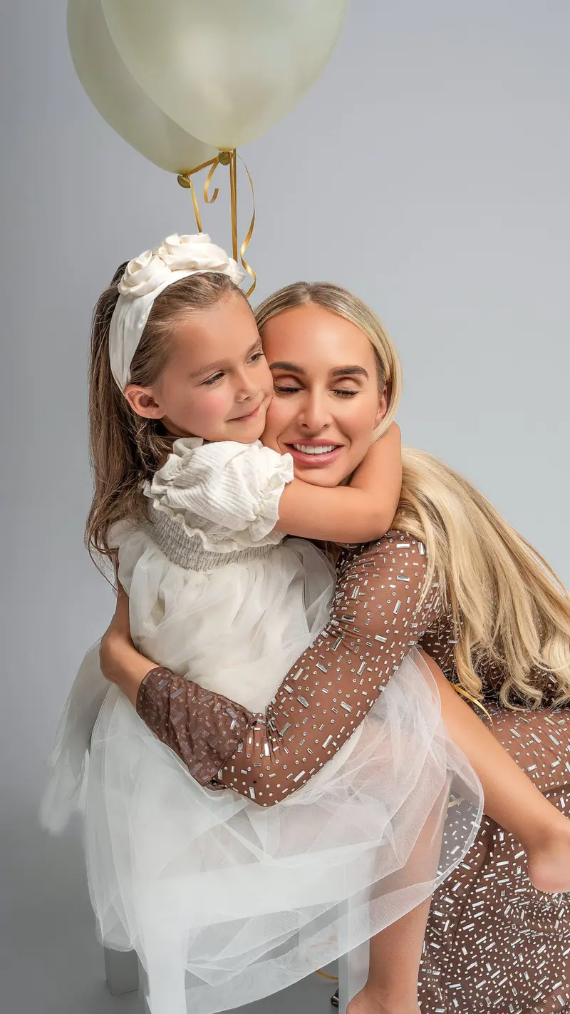 Fotenie mama a baby — mama a dcérka v objatí, biele balóny, trblietavé šaty