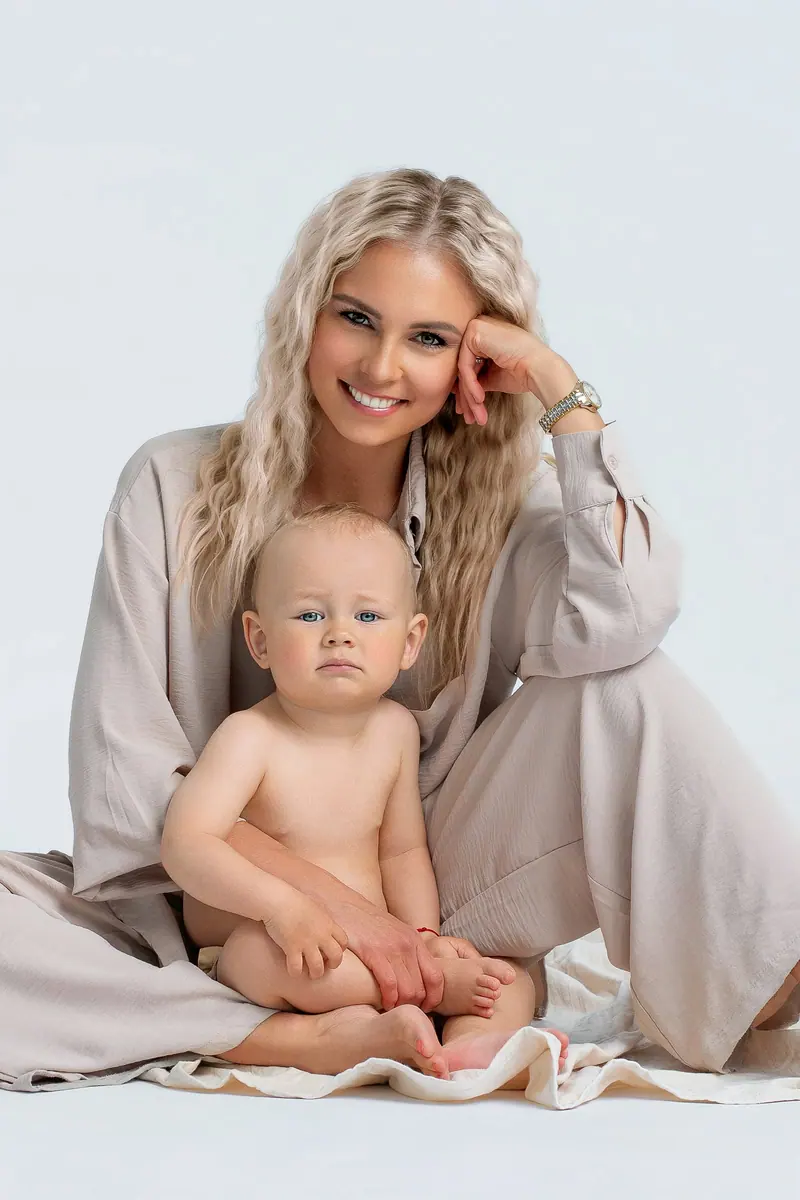 Fotenie mama a baby — blond mama v béžovom kabáte sedí s bábätkom