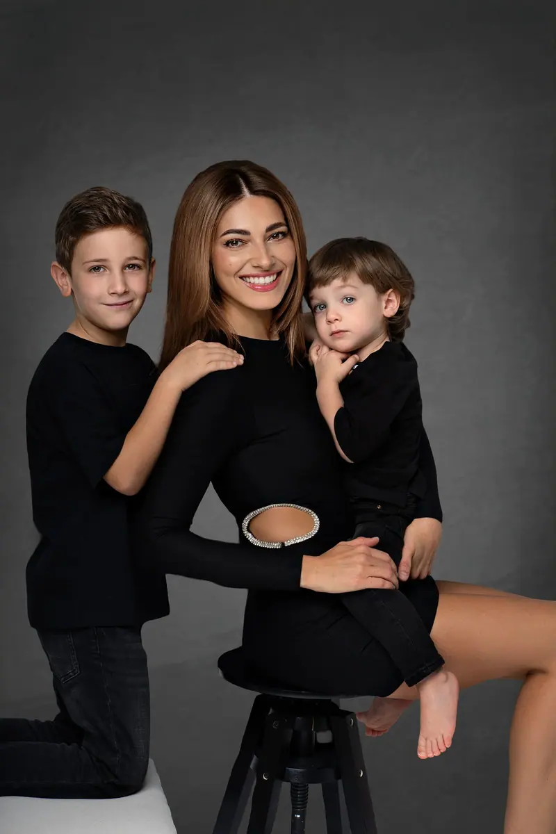 Fotenie mama a baby — mama s dvomi synmi v čiernom, tmavé pozadie