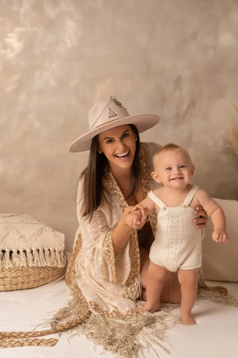 Fotenie mama a baby — mama v klobúku drží stojace bábätko, boho scéna