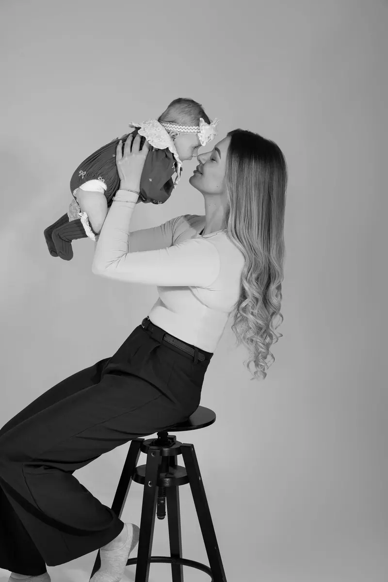 Fotenie mama a baby — mama na barovej stoličke dvíha bábätko nad seba — čiernobiela