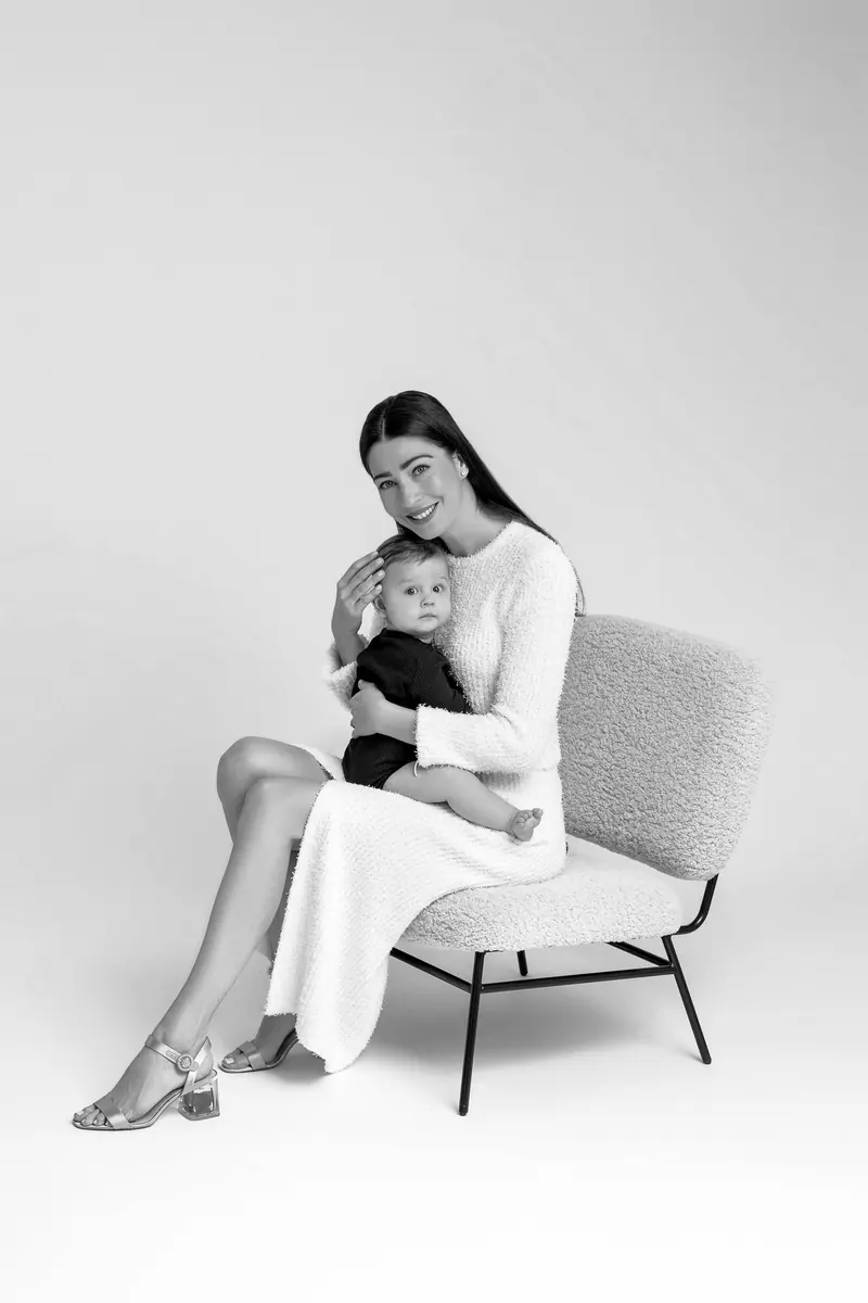 Fotenie mama a baby — mama v kresle s bábätkom na kolenách — čiernobiela