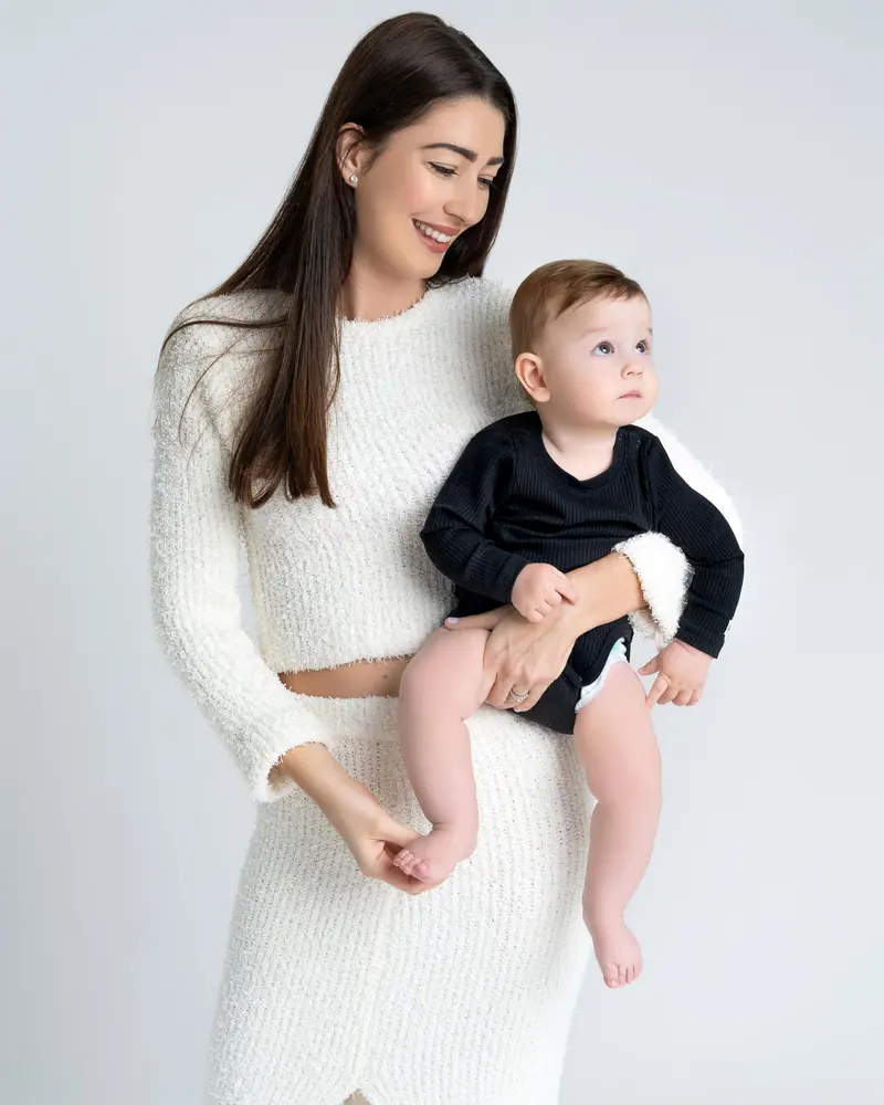 Fotenie mama a baby — mama v bielom pletenom komplete drží syna v čiernom body