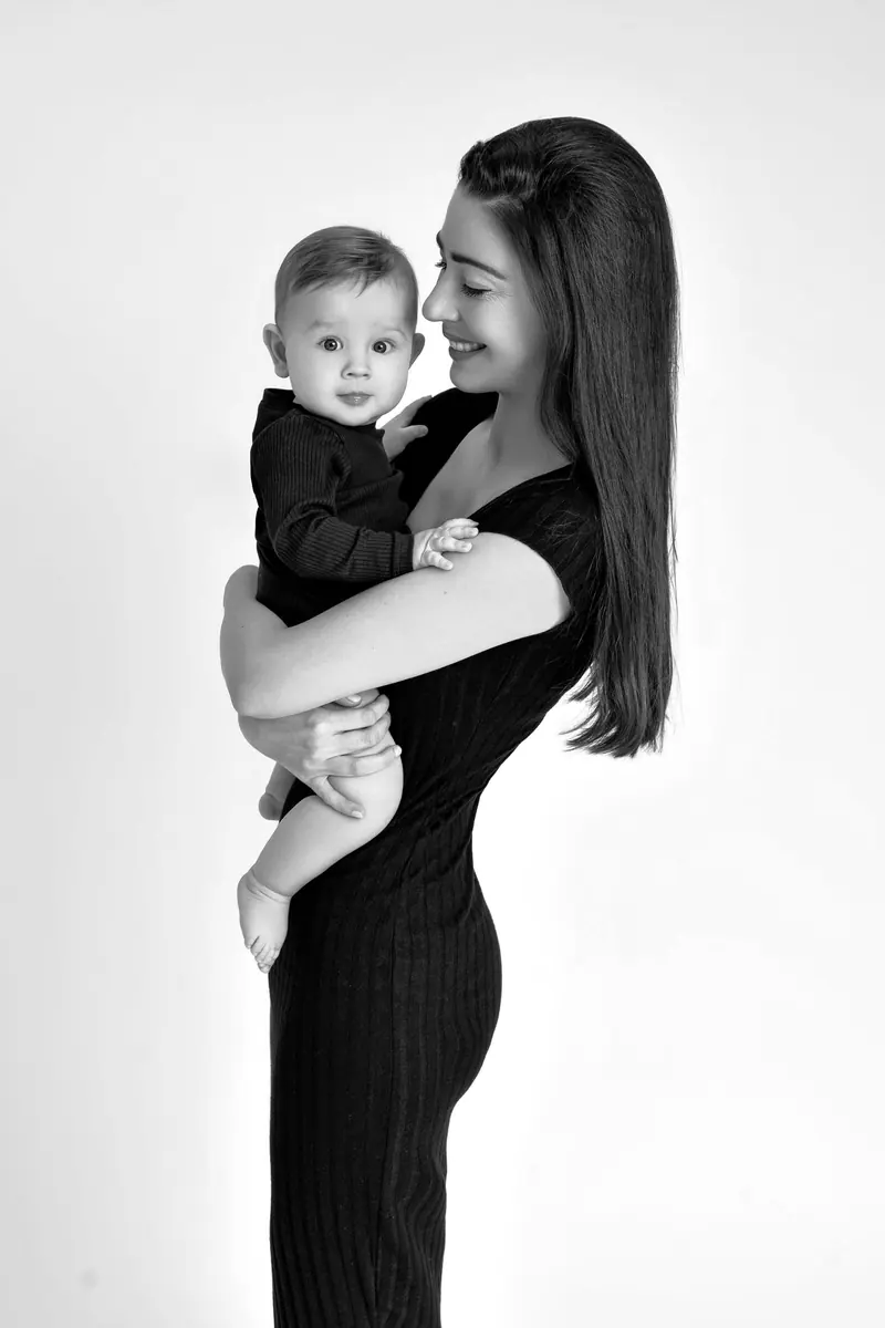 Fotenie mama a baby — mama v čiernych šatách drží syna, profil — čiernobiela