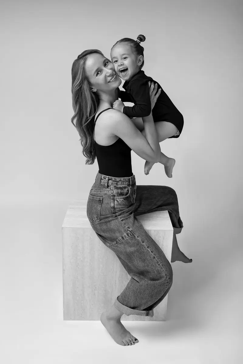 Fotenie mama a baby — mama v džínsoch s dcérkou na kocke, smiech — čiernobiela