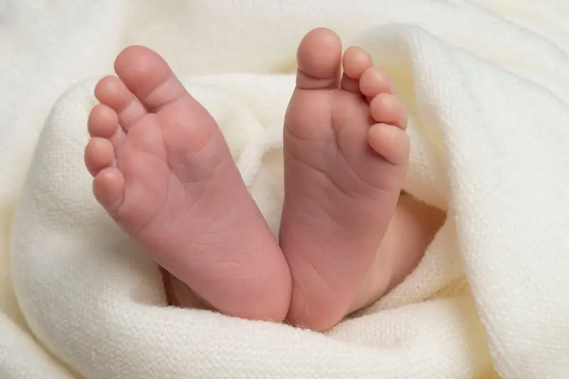 Newborn fotenie — detail chodidiel novorodenca v bielej deke