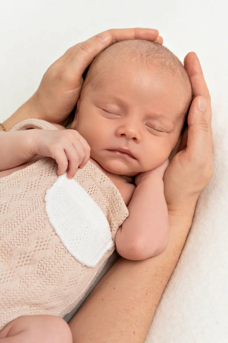 Newborn fotenie — novorodenec v rukách rodiča, béžové oblečenie