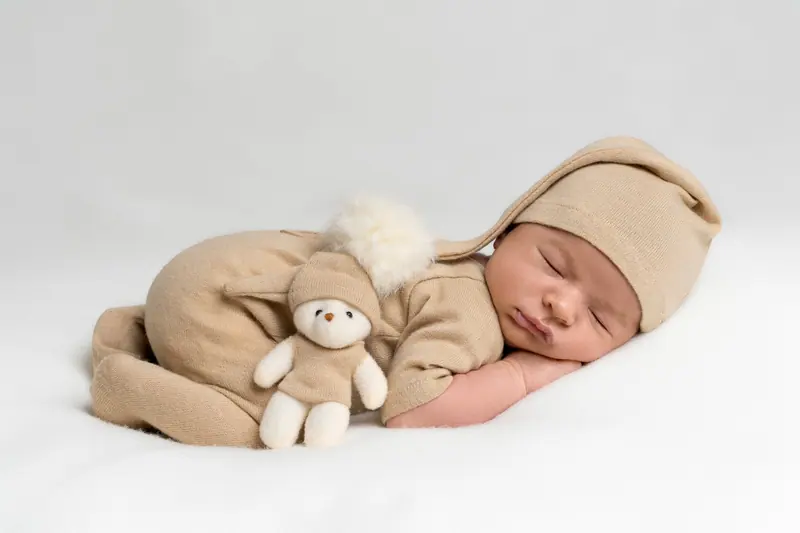 Newborn fotenie — novorodenec v béžovej čiapke s plyšovou hračkou