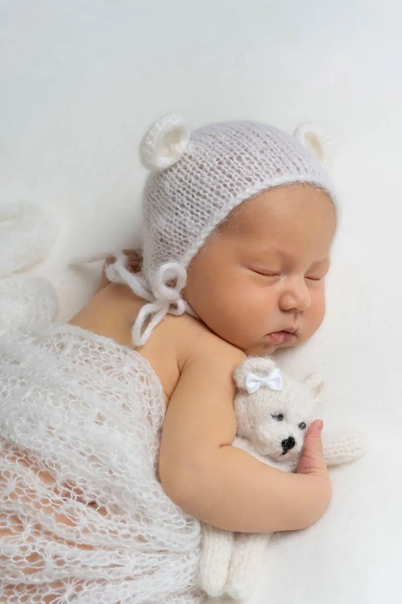 Newborn fotenie — novorodenec v čiapke s uškami drží plyšového medvedíka