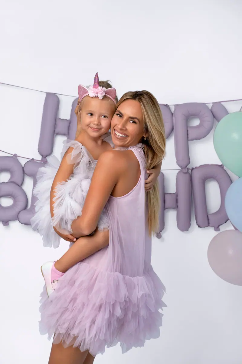 Narodeninové fotenie — mama drží dcérku s jednorožcovou čelenkou, fialové balóny „Happy Birthday“