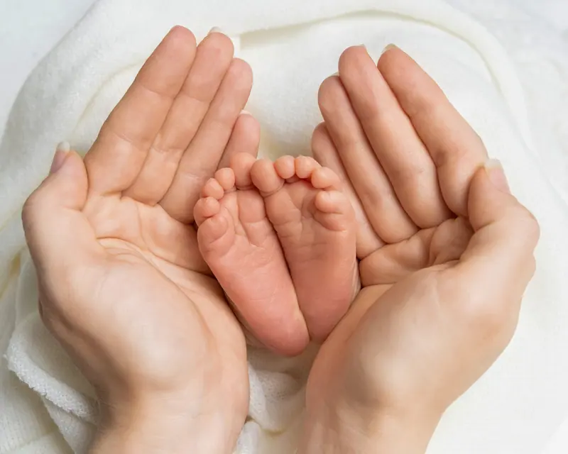 Newborn fotenie — detail chodidiel bábätka v dlaniach rodiča