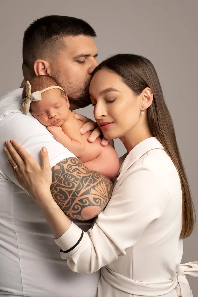 Newborn fotenie — rodičia s novorodencom — otec bozkáva mamu, krémové oblečenie