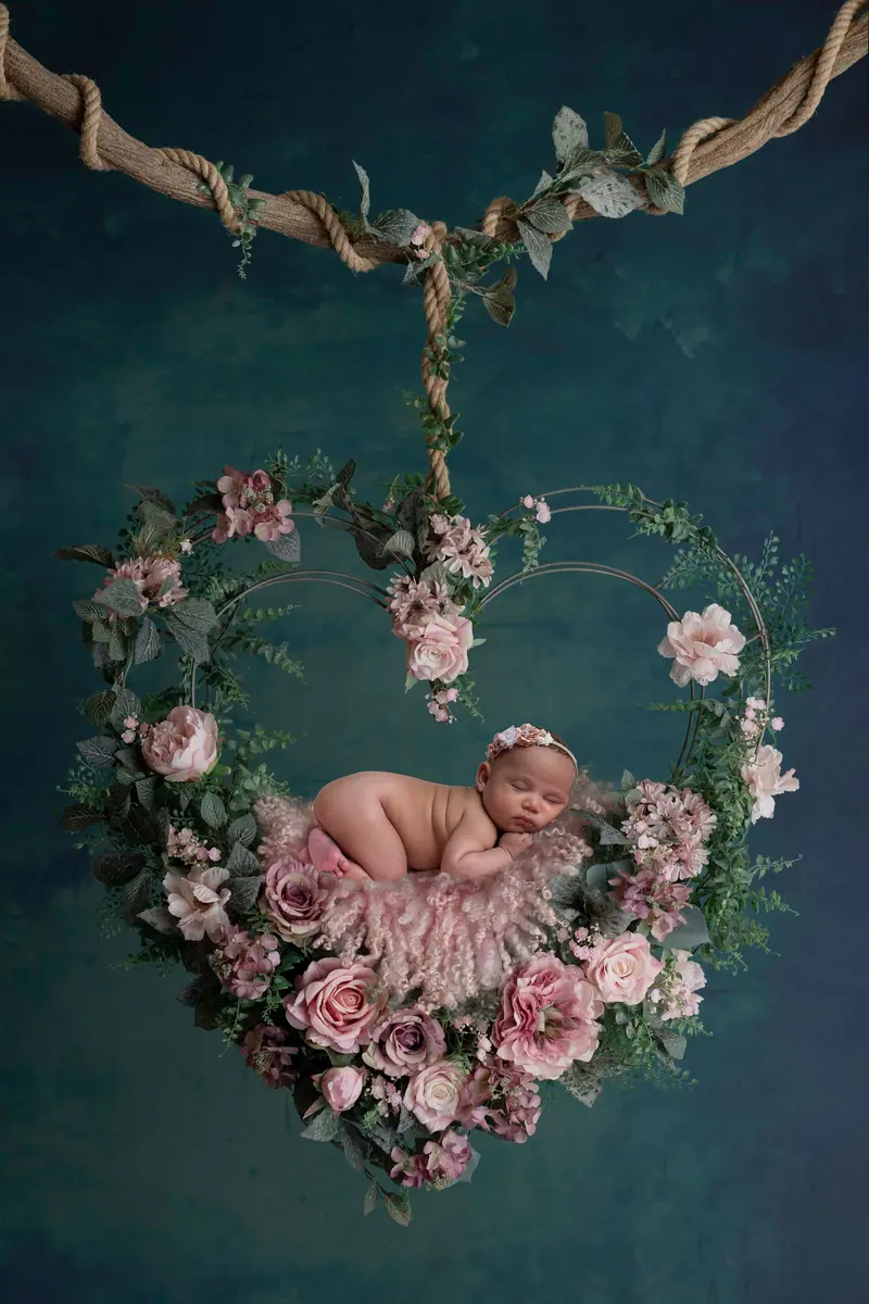 Newborn fotenie — novorodenec v kvetinovom srdci na lane, zelené pozadie