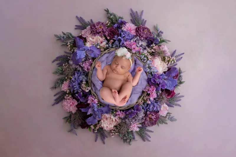 Newborn fotenie — novorodenec vo fialovom kvetinovom venci, zhora