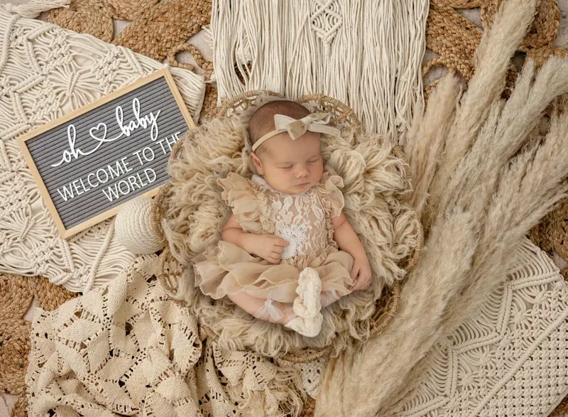 Newborn fotenie — bábätko v boho košíku s tabuľkou „oh baby, welcome to the world“