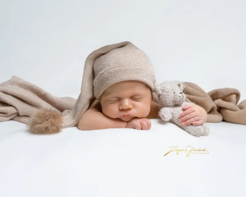 Newborn fotenie — bábätko v béžovej čiapke s plyšovým medvedíkom