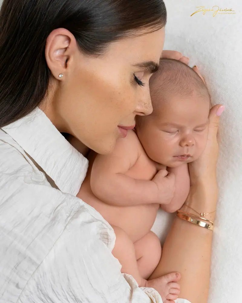 Newborn fotenie — mama pritúlená k bábätku, detail z profilu