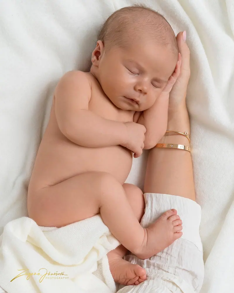 Newborn fotenie — bábätko schúlené v maminom náručí, krémové tóny