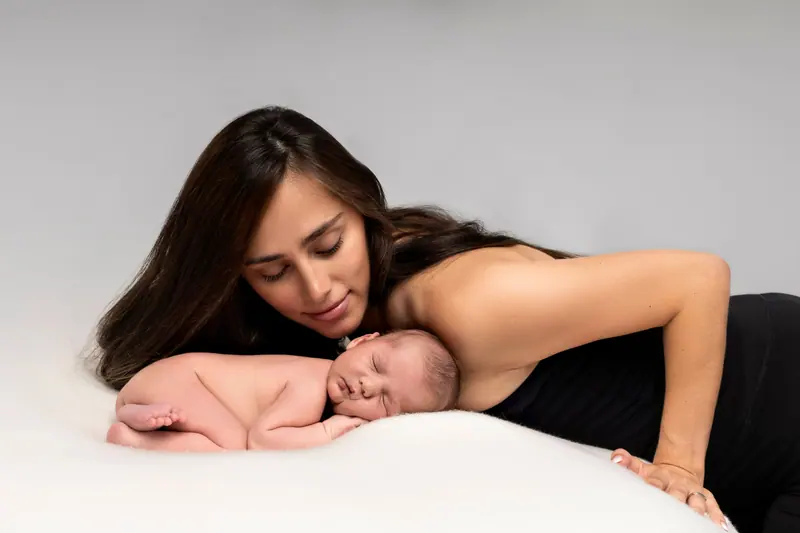 Newborn fotenie — mama sa skláňa nad novorodencom