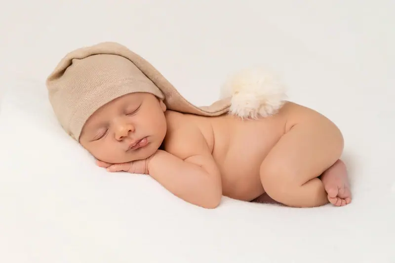 Newborn fotenie — novorodenec v béžovej čiapke s brmbolcom