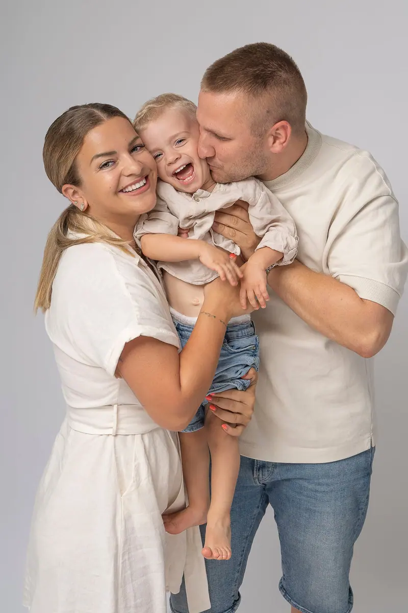 Rodinné fotenie — otec bozkáva syna, mama sa smeje
