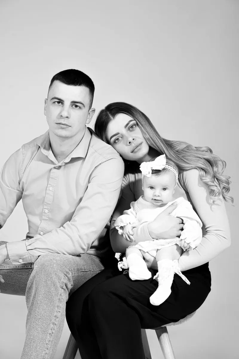 Rodinné fotenie — rodičia s bábätkom na kolenách — čiernobiela