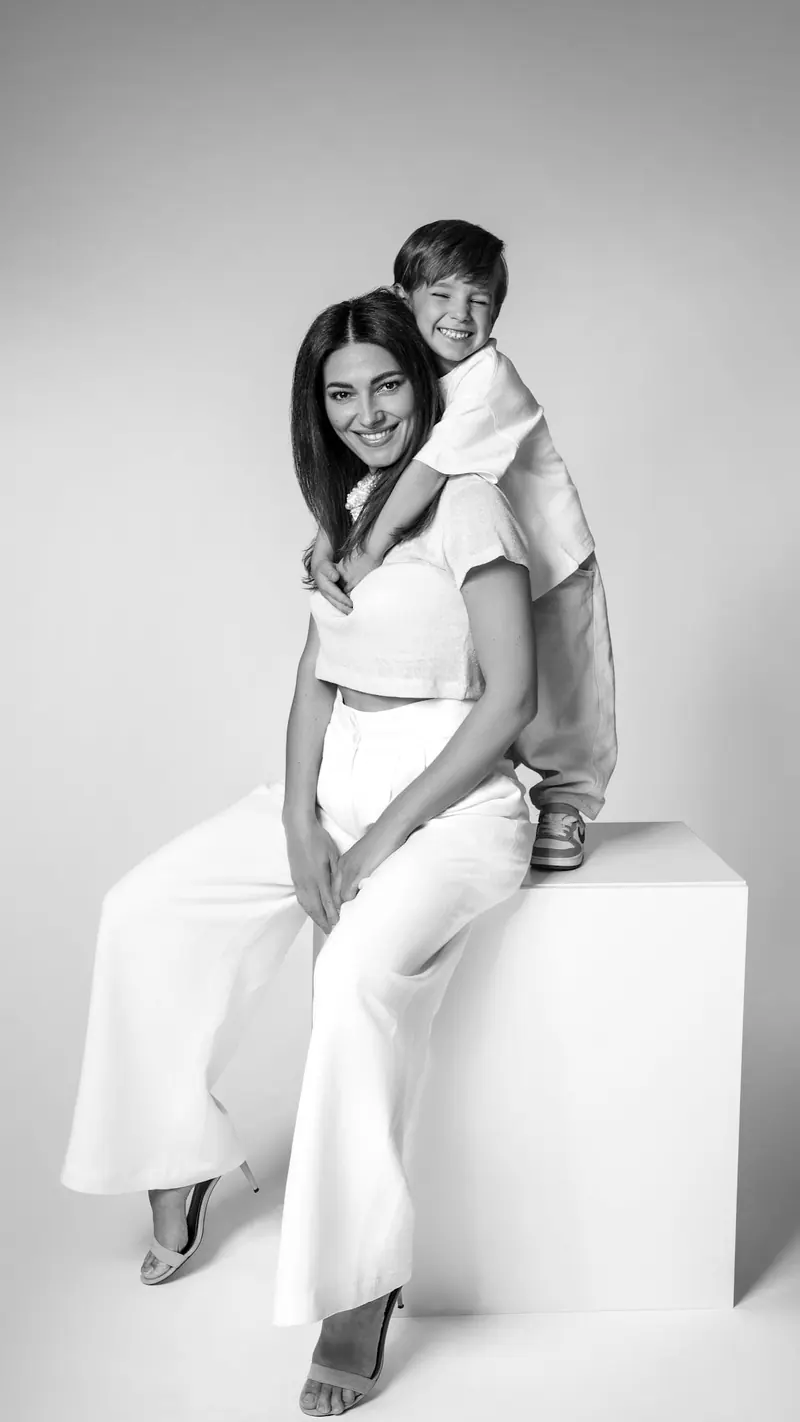 Rodinné fotenie — mama sedí na kocke, syn ju objíma zozadu — čiernobiela