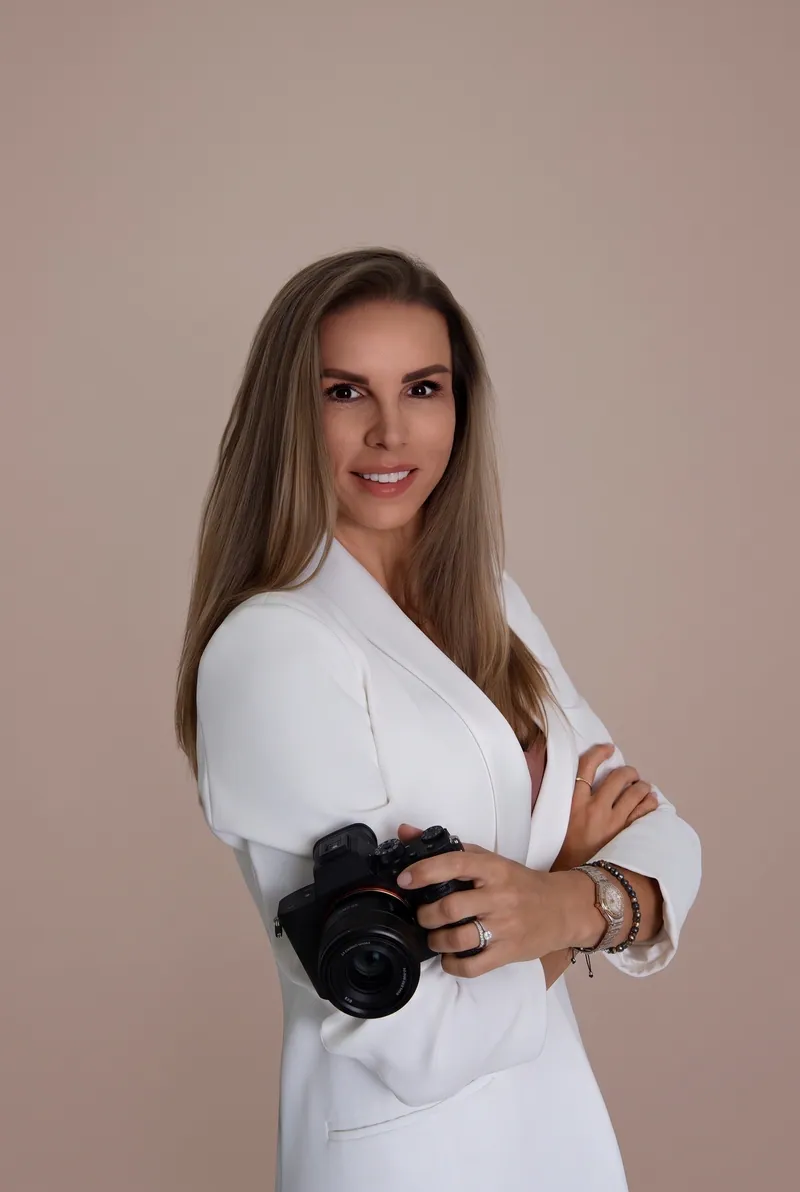 Zuzana Jánošová v bielom saku s fotoaparátom v ruke
